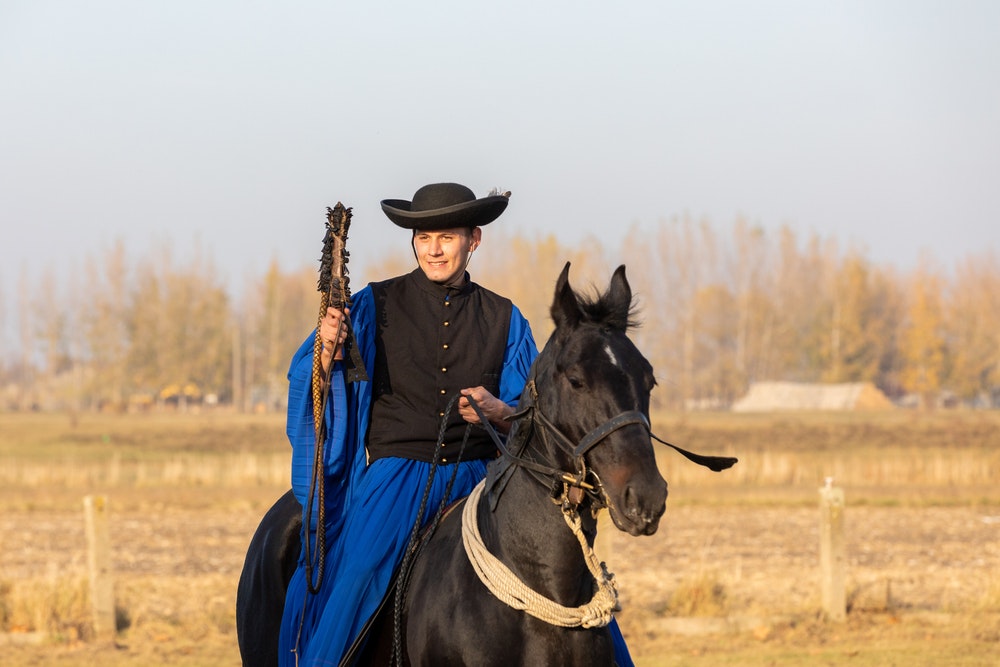 Maďarský csikos v tradičním lidovém kroji předvádí svého cvičeného koně. 