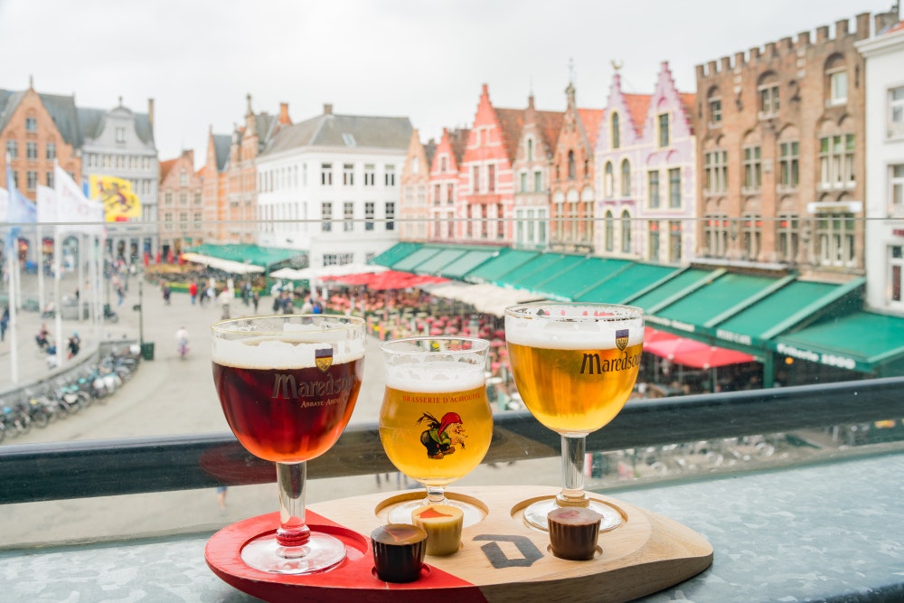 Belgická piva, v pozadí město Bruggy