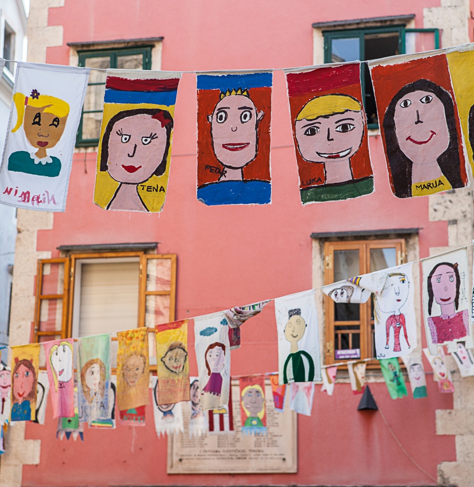 A view of the historic old town during an art festival for children. The city is decorated with children's drawings.
