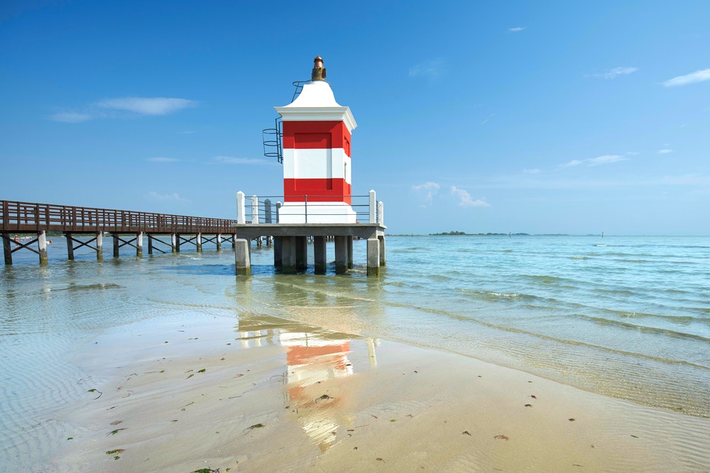 Old lighthouse on the beach in Lignano with a red and white facade