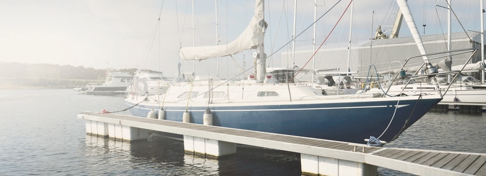 Ein schnittiges und modernes Segelboot, das bei klarem Wetter an einem Pier in einem Yachthafen festgemacht hat.
