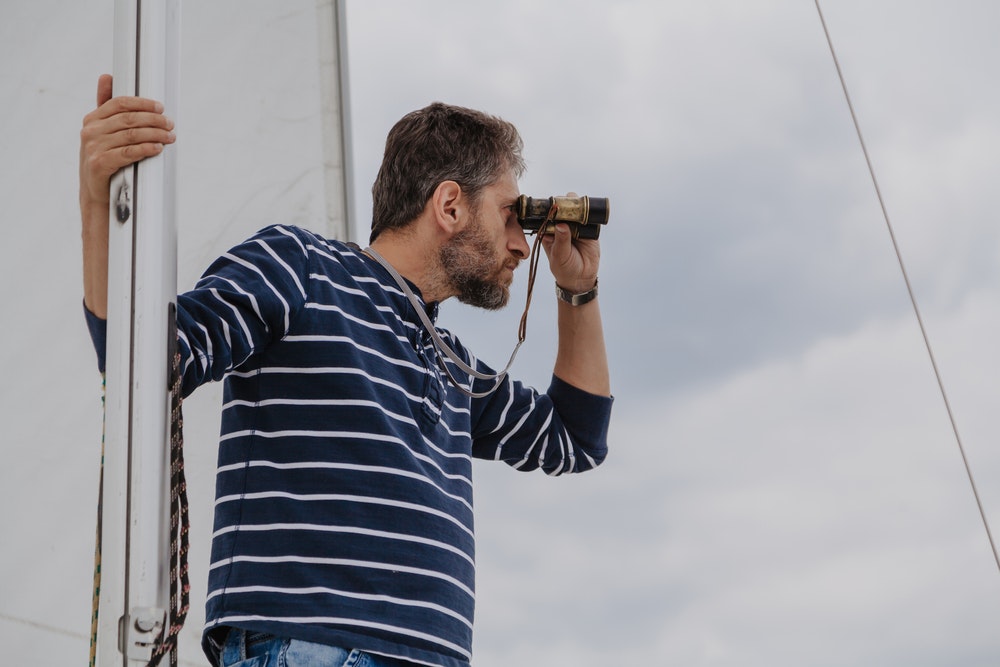 The captain of the ship looks through binoculars.
