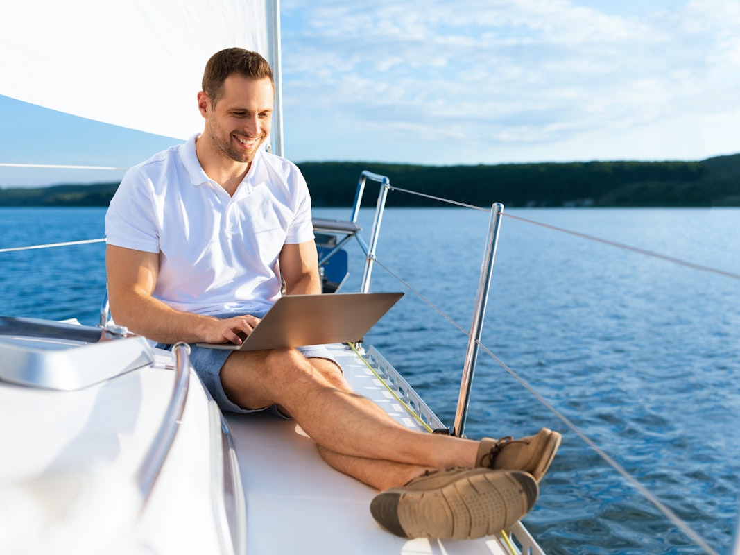 Uomo con computer portatile sulla prua della barca