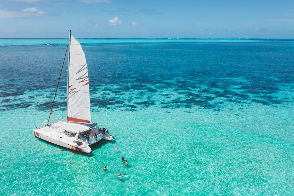 Family and friends bathing by a beautiful catamaran in a turquoise lagoon off the coast of Mauritius