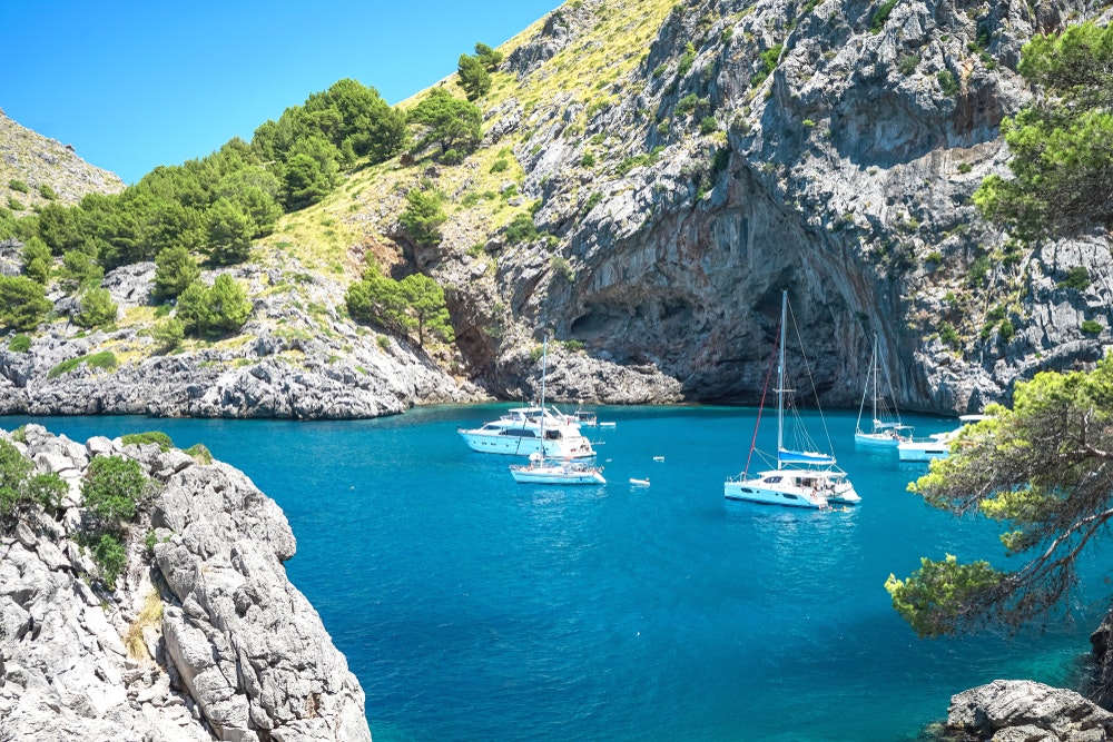 plachetnice  akatamarány v tyrkysové hzátoce u skalisek na ostrově Mallorca