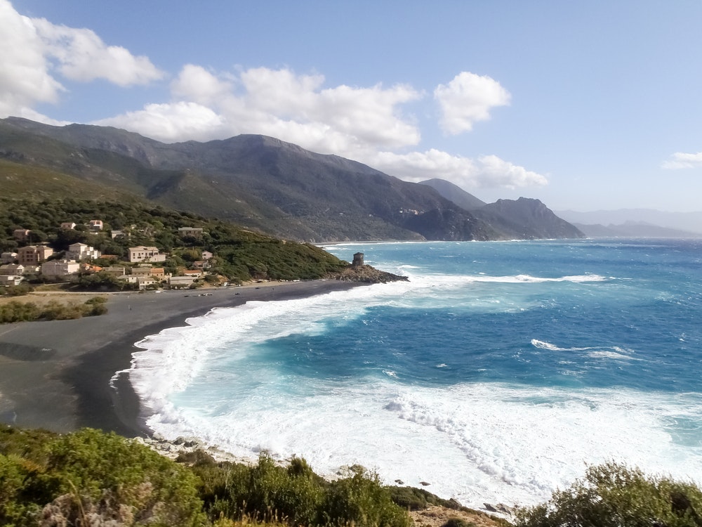 Pobřeží ostrova Korsika, pláž Nonsa, rozbouřené moře plné pěny kvůli vítru mistrál.