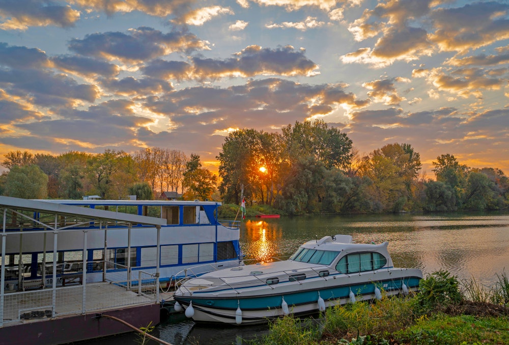 Beautiful sunrise by the Tisza River with a houseboat moored 