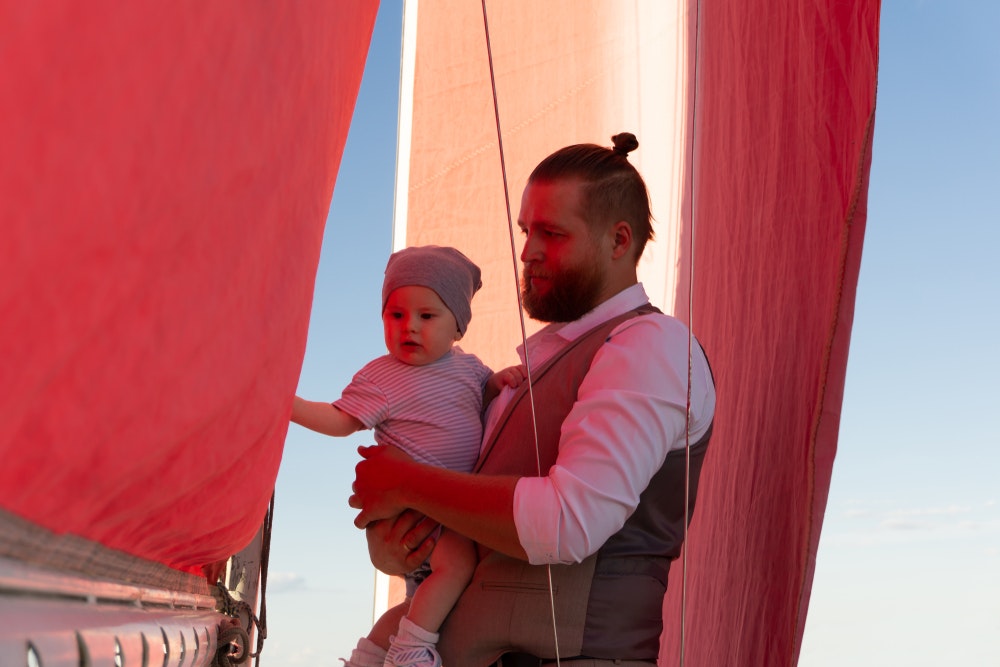  Ein Mann hält ein Kind in seinen Armen an Bord eines Schiffes.