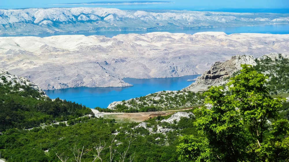 Blick vom Velebit-Gebirge auf den grünen Wald und das Mittelmeer auf den weißen, trockenen Inseln von Pag, Kroatien.