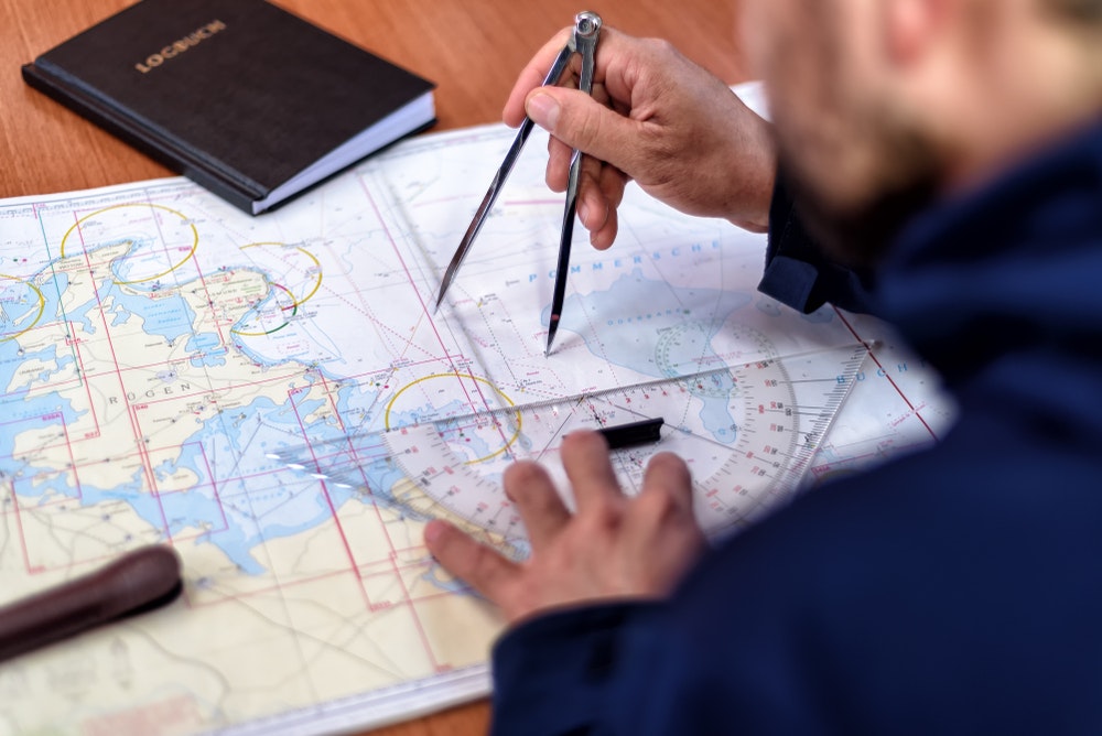 A captaion planning sailing route with sailing equipment.
