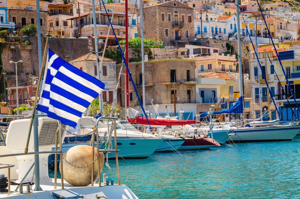 Γαλάζια λευκή ελληνική σημαία και αέρας σε ένα ελληνικό λιμάνι γεμάτο πλοία, Κως, Ελλάδα