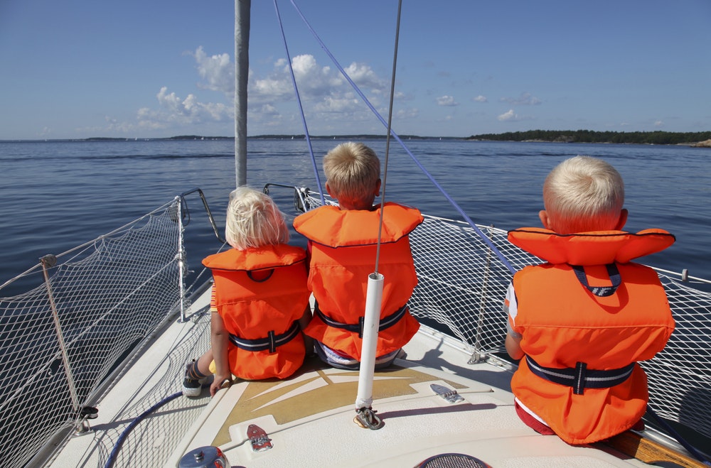Παιδιά που κάθονται στην πλώρη ενός πλοίου με σωσίβια.
