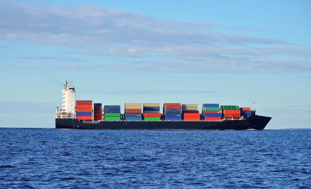 Černá kontejnerová loď plující v klidné vodě poblíž přístavu Riga
