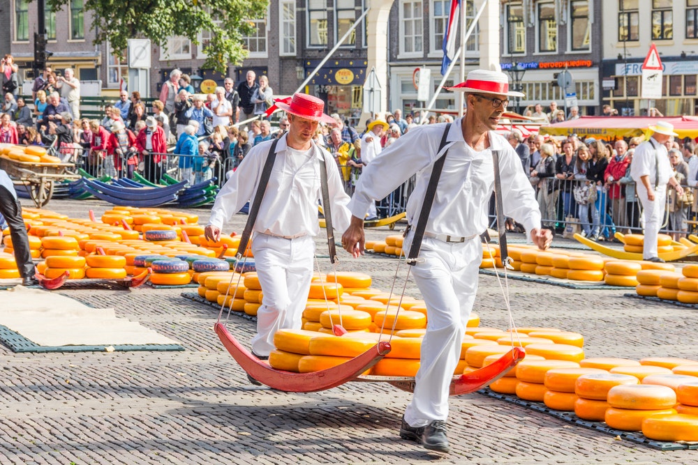 Nosiči se spoustou sýrů na slavném nizozemském sýrovém trhu v nizozemském Alkmaaru na náměstí Waagplein.