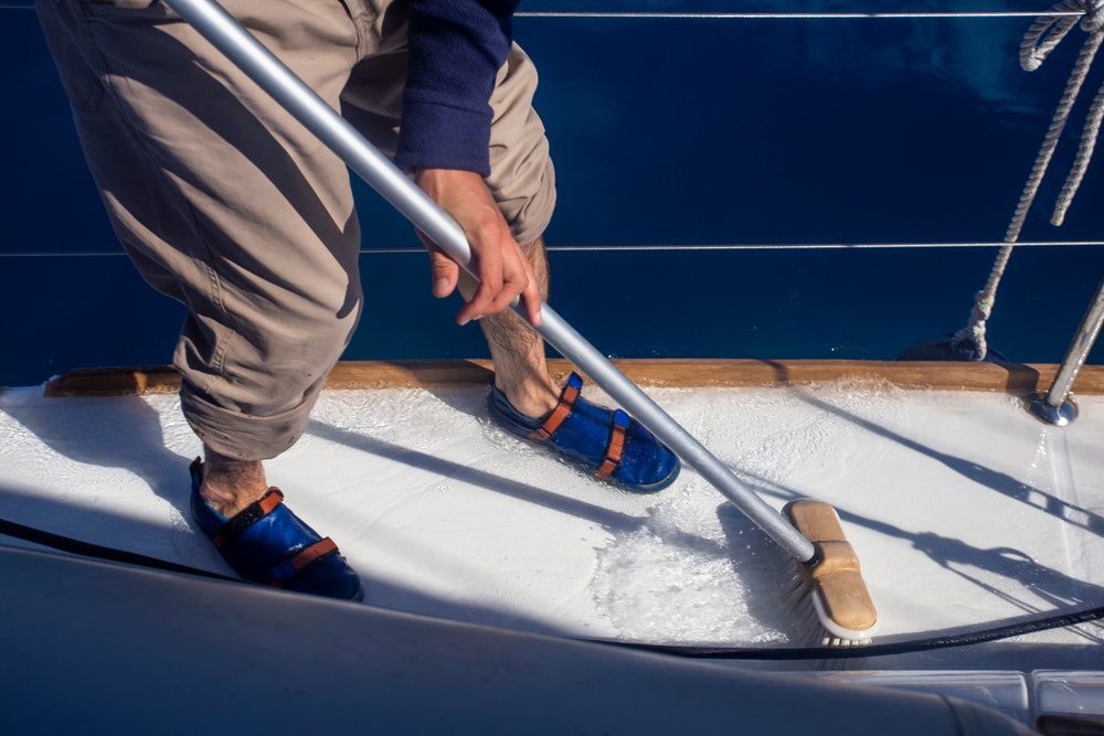A man mops the deck of a yacht