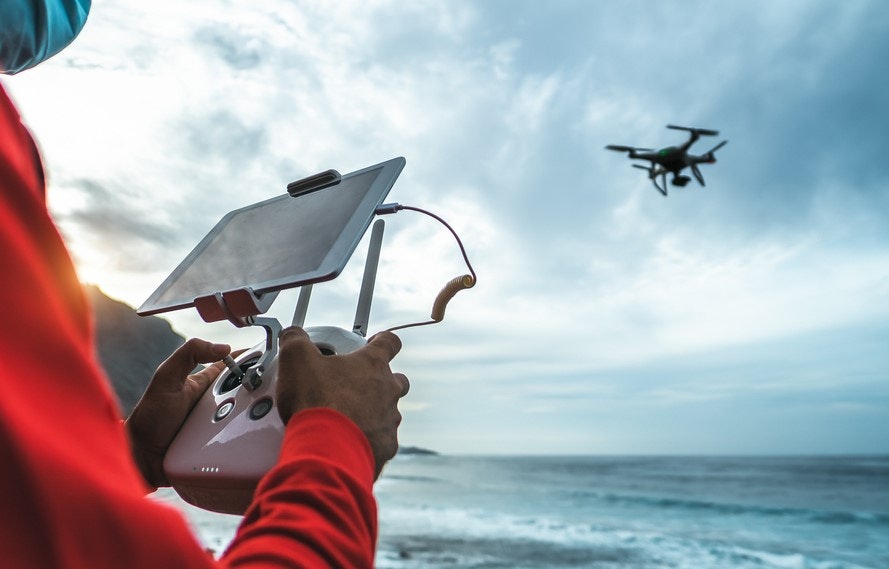 Mann steuert eine Drohne über dem Meer