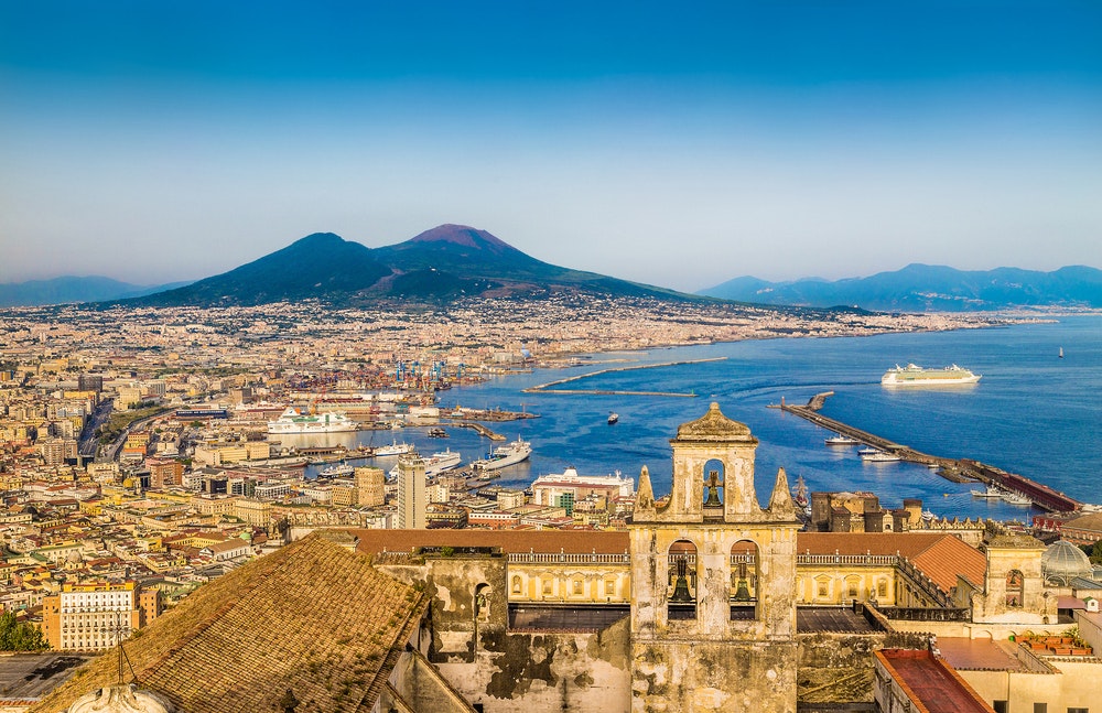 Picturesque view of the city of Naples with the famous Vesuvius in the background in the golden evening light at sunset, Campania, Italy