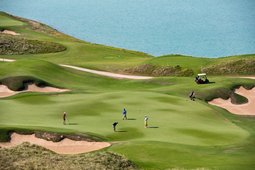 Golf resort and players by the seashore.