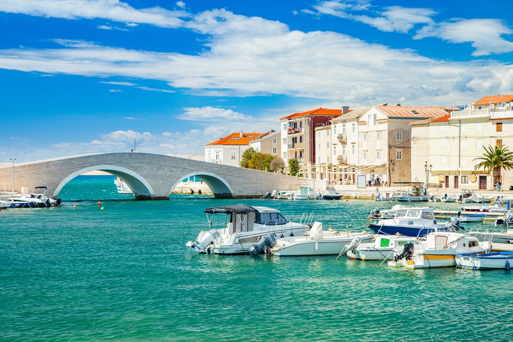 Gražus Pago miestas prie Adrijos jūros Dalmatijoje, Kroatijoje, senas akmeninis tiltas, krantinė ir uostas su valtimis