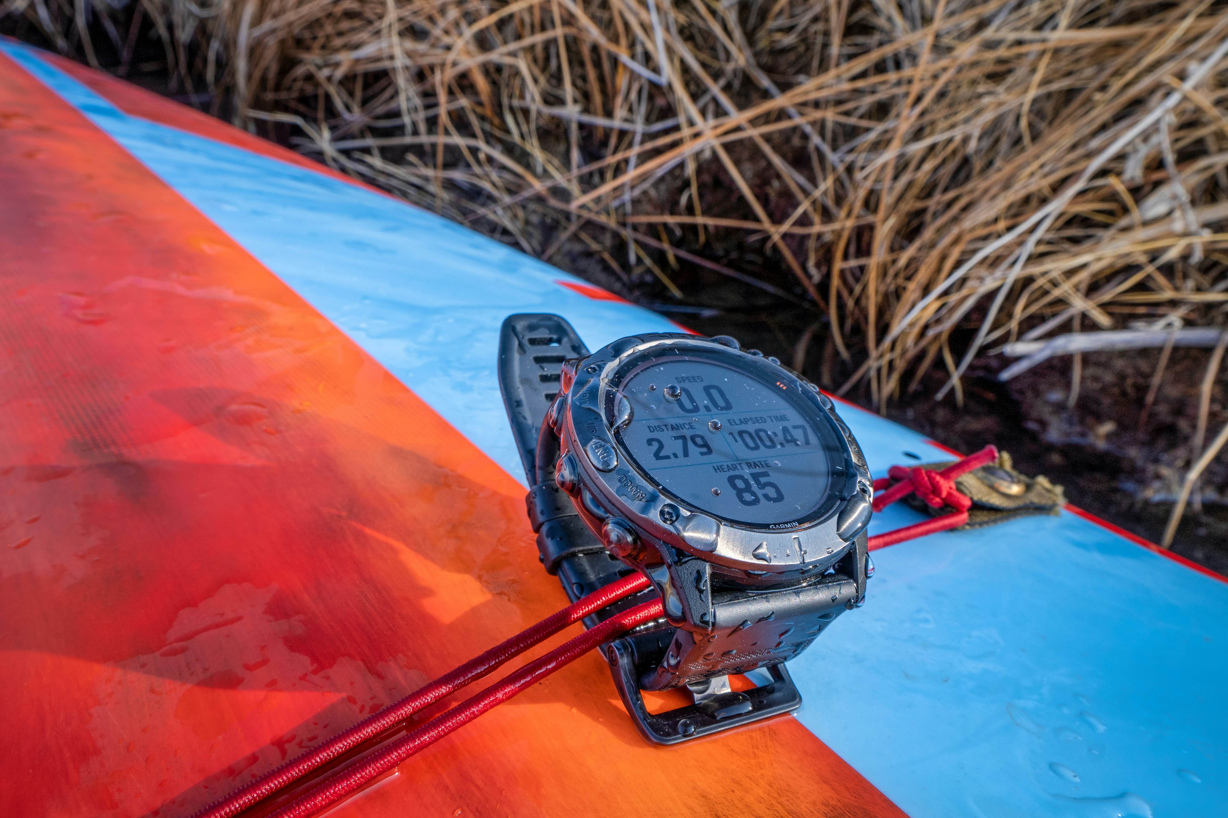 "Garmin fenix Pro 6X" saulės baterijos laikrodis ant stovinčios irklentės denio su treniruočių laikrodžio ciferblatu.