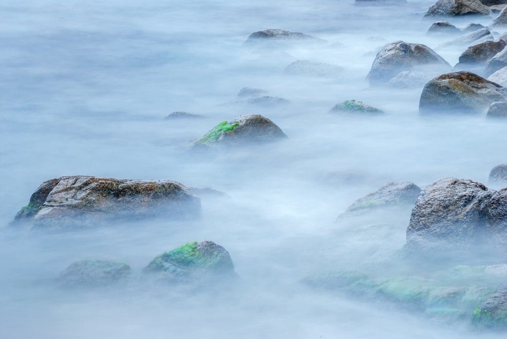 Kameny u pobřeží v mlze.