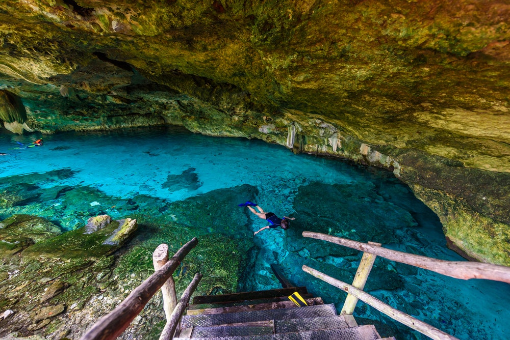 Cenote Dos Ojos in Quintana Roo near Tulum on the Yucatán Peninsula in Mexico. People swim and snorkel in the clear blue water. 