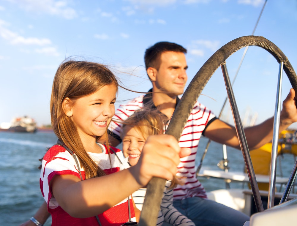 Ung far med bedårende døtre som hviler på en stor båt