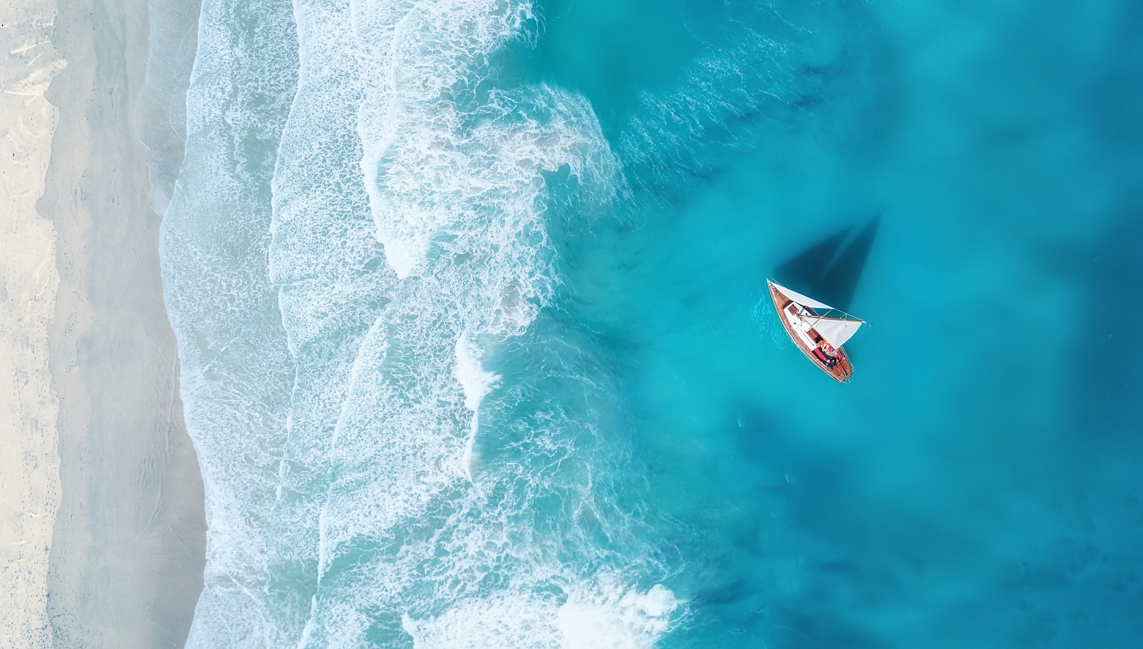 A yacht on the water surface seen from above. Turquoise water background seen from above. Summer seascape from the air. 