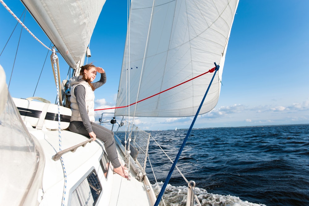 A woman on a sailboat looks into the distance.