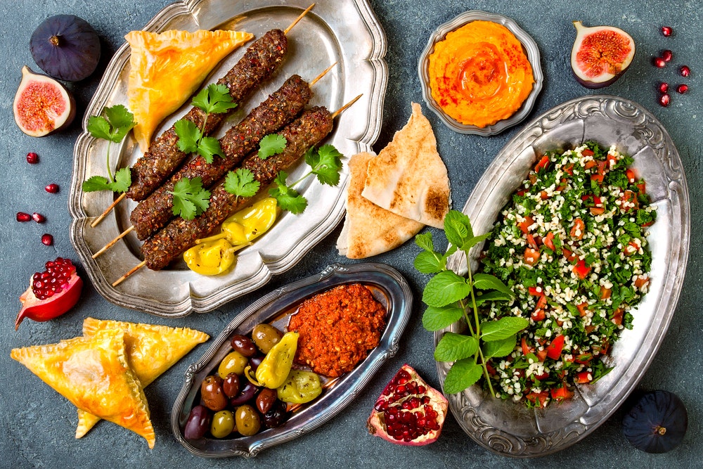 A traditional Middle Eastern dinner. Olives, salad, skewered meat, hummus.