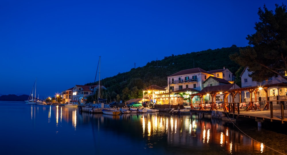 Båter fortøyd foran en restaurant i Kroatia, natt- og gatelys