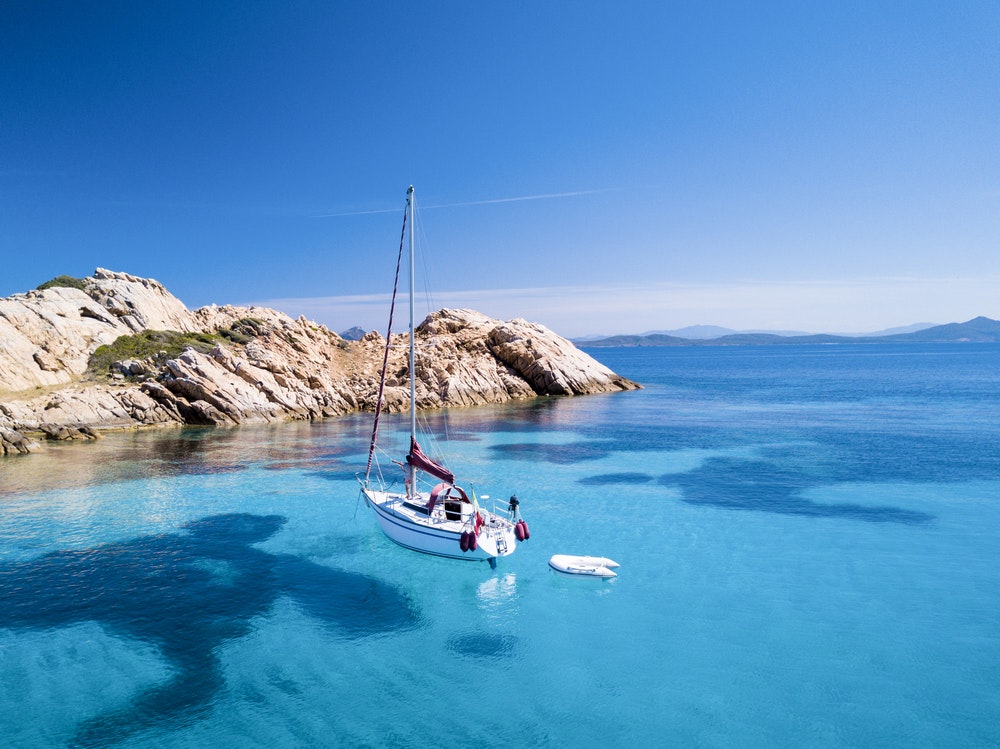 Burlaivis priešais Mortorio salą Sardinijoje. Nuostabus paplūdimys su turkio spalvos ir skaidria jūra. 
