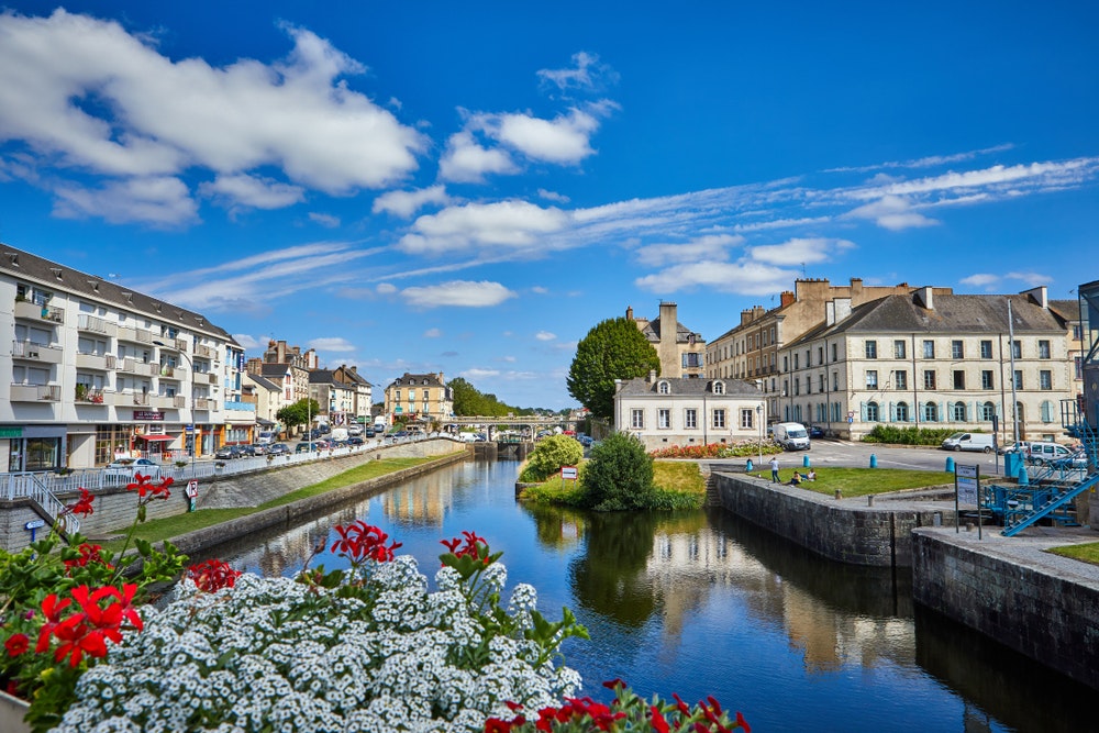 Pohled na vodní kanál ve městě Redon, Bretaň, Francie, slunné počasí, most, květiny.