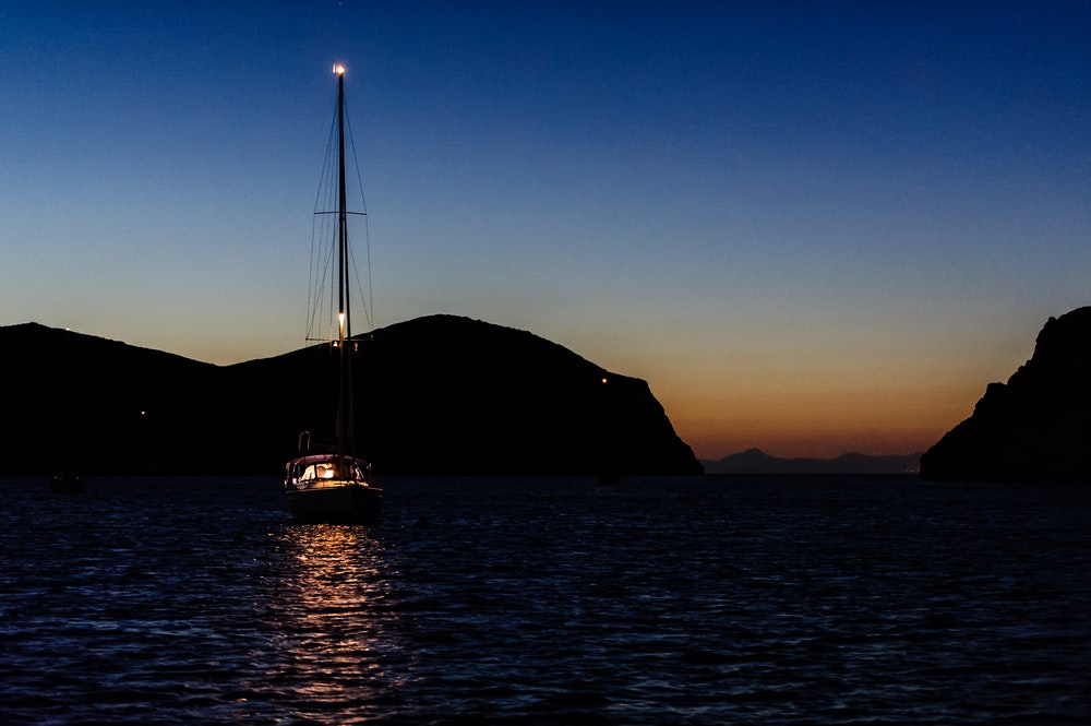 A boat moored in a bay at night with an anchor light on. 