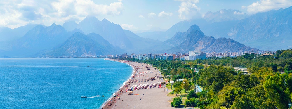 Panoramatický výhled na Antalyi a pobřeží Středozemního moře, pláž a krásné hory v mracích.