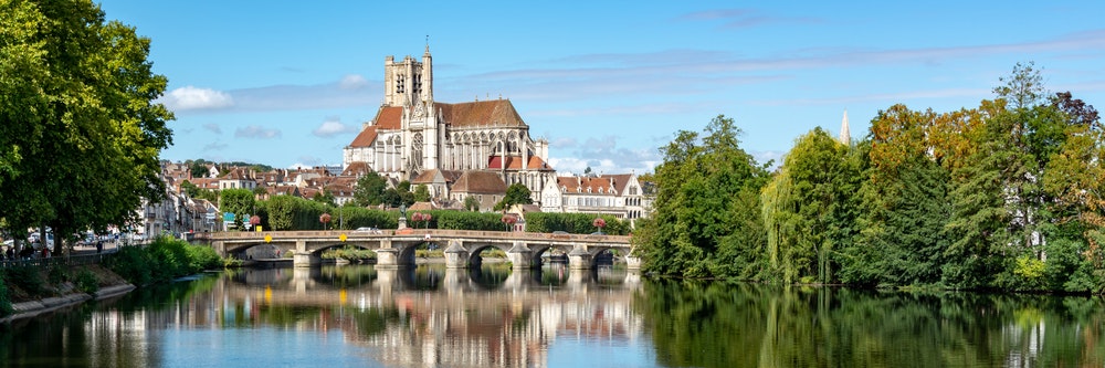 Řeka Yonne a kostel v Auxerre v Burgundsku