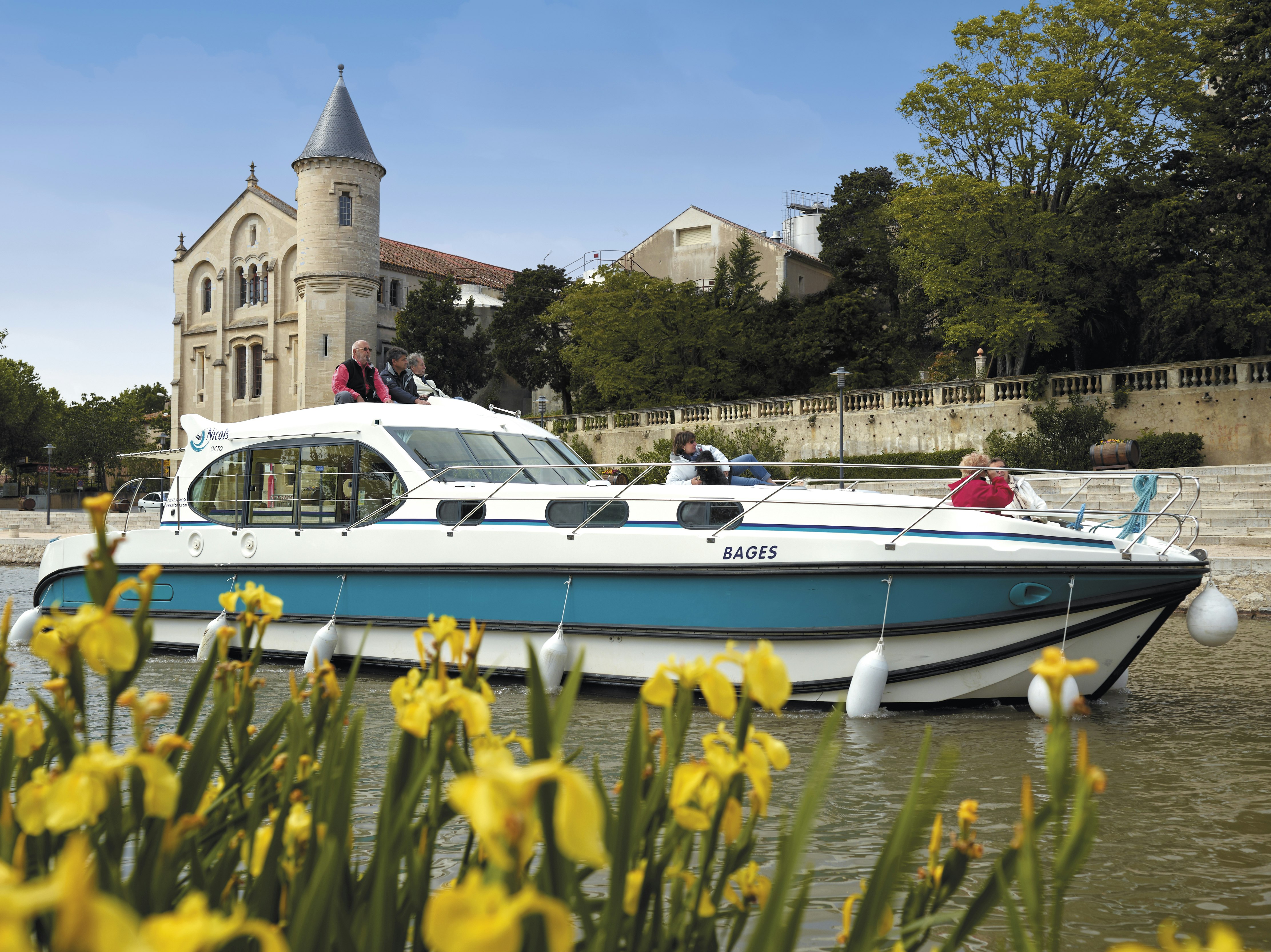 Ein Hausboot schippert an einem historischen Schloss in Frankreich vorbei.