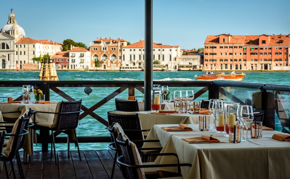 Pohled z restaurace na benátkou lagunu, prostřené stoly