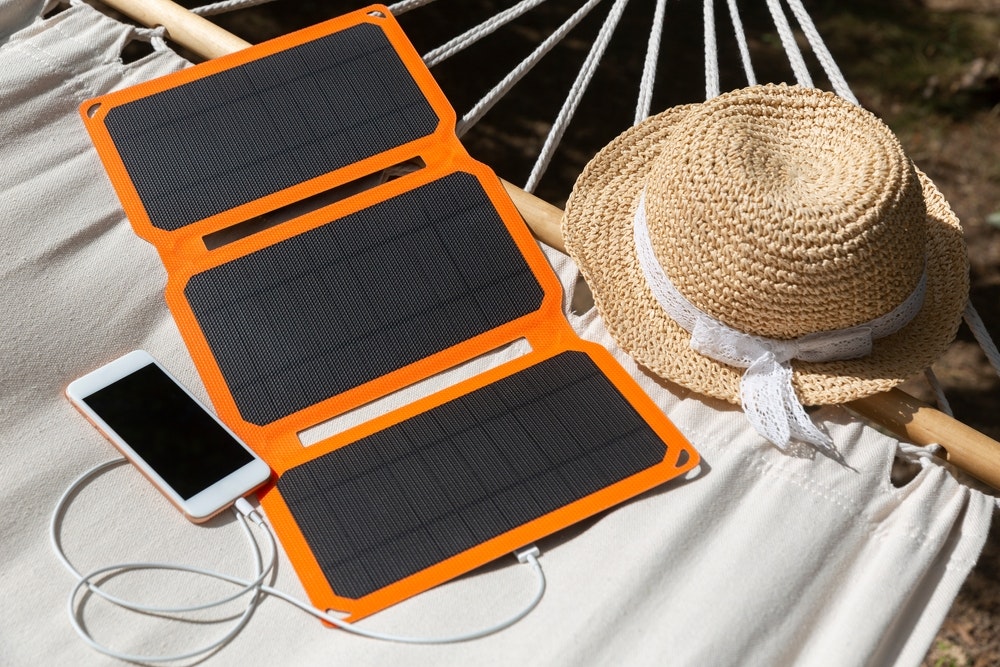 A smartphone is charged by a solar battery at summer camp.