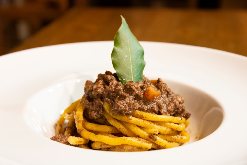 Trebord med Bigoli pasta og Amarone saus (en typisk italiensk rett), rødvin og brød.