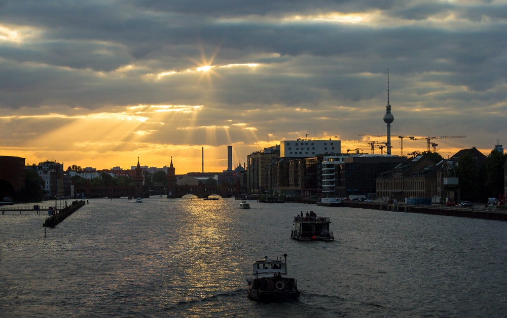 Berlín při západu slunce, panorama města s pohledem na řeku a lodě, hausbóty.