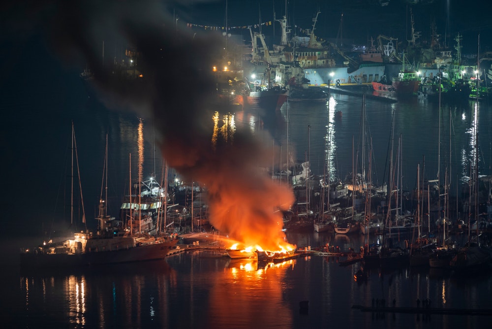 Segelboote im Yachthafen brennen in der Nacht, dunkler Rauch, Gefahr