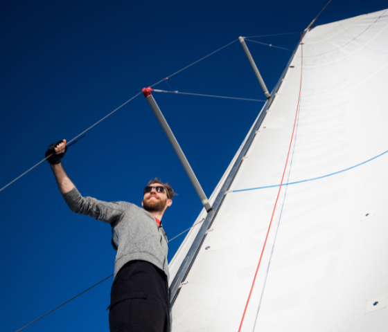 Sailor standing by a sail on a boat