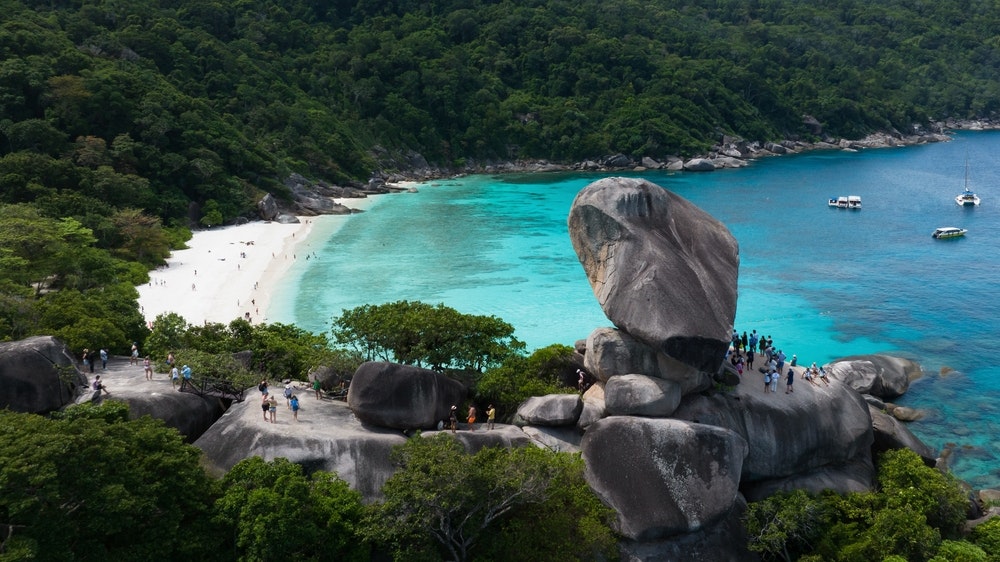 Similan Adaları'ndaki kaya oluşumları, arka planda körfezin yer aldığı bir manzara noktasında insanlar