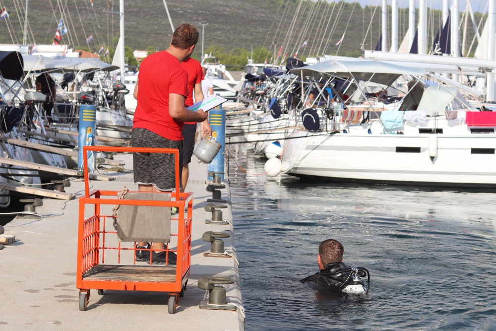 Potápěč se potápí v přístavu poblíž mola s plachetnicemi. 