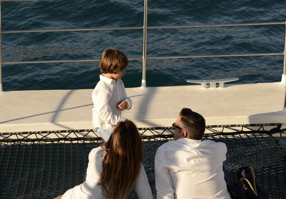 Mom, dad and son lying on the net of a big catamaran.