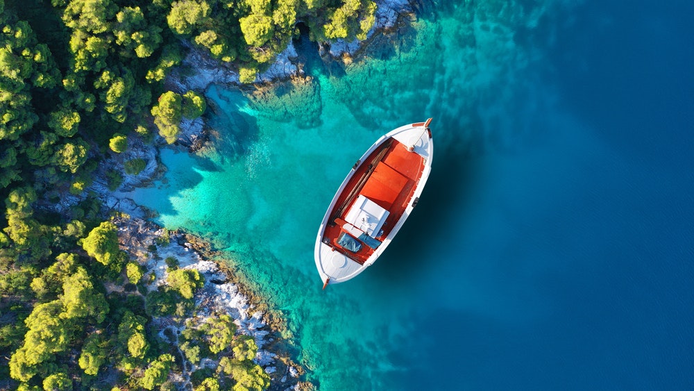 Agnontas, Skopelos, Sporades'in küçük pitoresk limanı yakınlarında demirlemiş geleneksel bir balıkçı teknesinin havadan çekilmiş fotoğrafı
