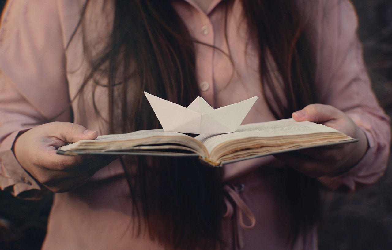 Folded paper boat and book