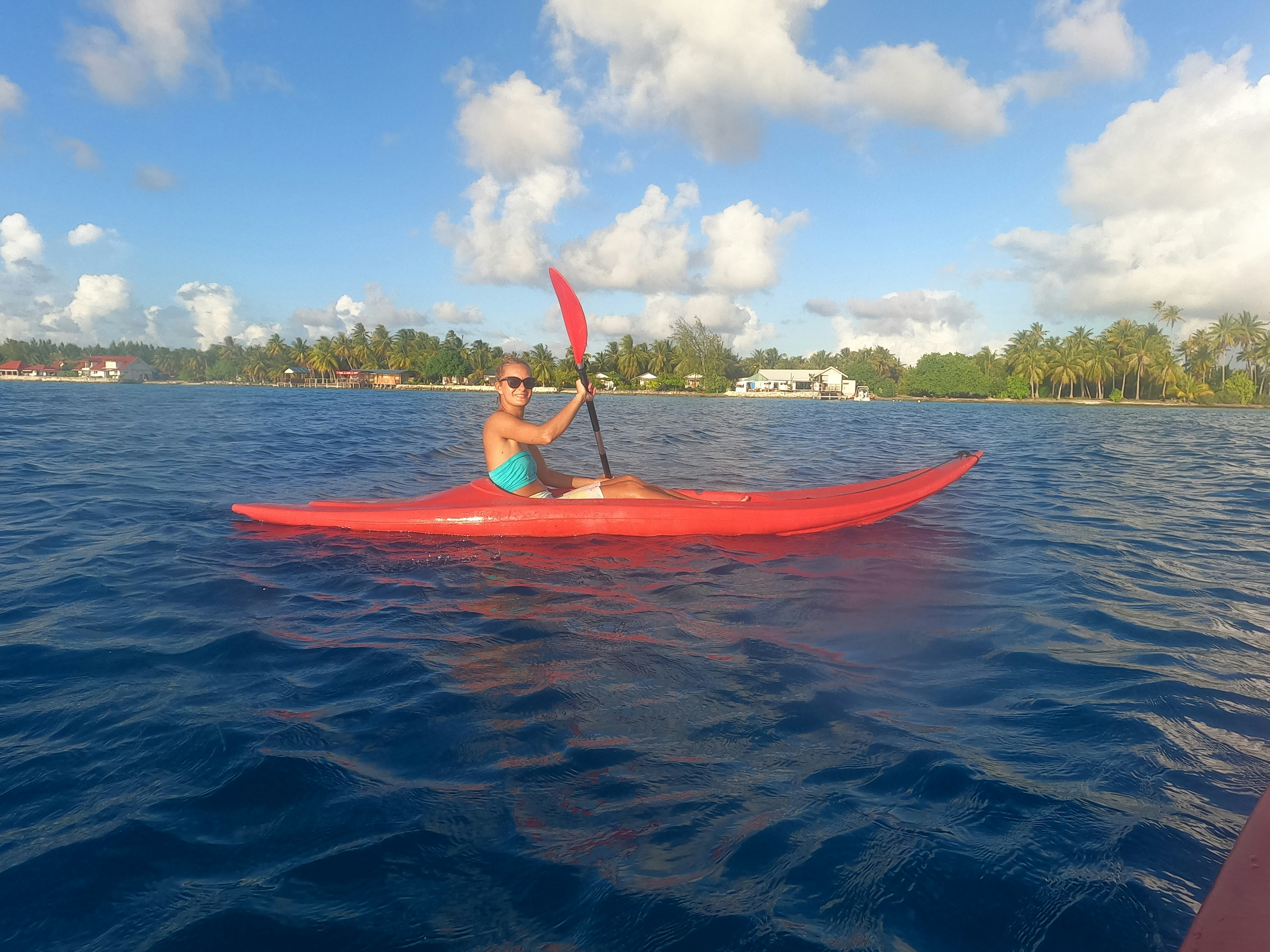 A woman in a red kayak in a bay in French Polynesia.