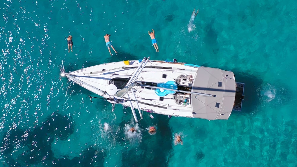 A view from above of young friends jumping off a sailboat. 